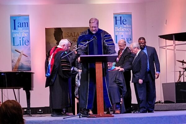 Dr. Bargerhuff and the board praying over Dr. Best and his wife.